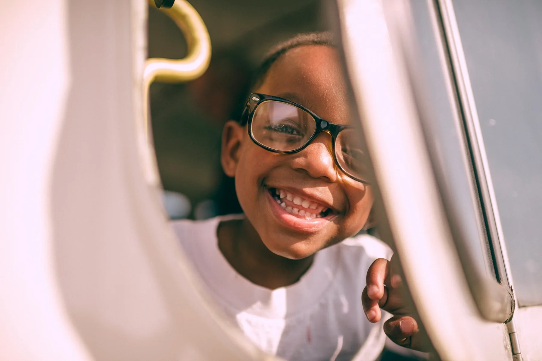 A smiling child looking through a playground opening